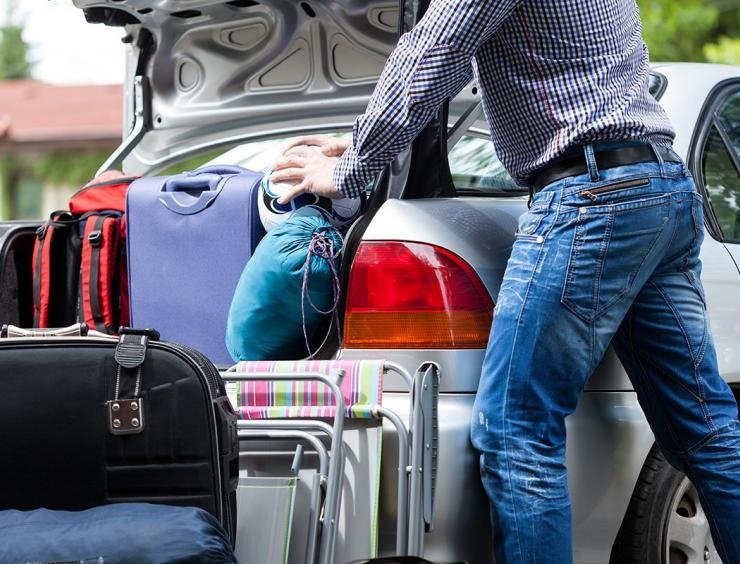 a man putting luggage in the trunk of a car