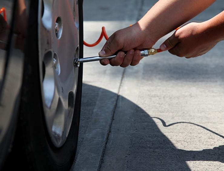 mies vaihtaa auton rengasta