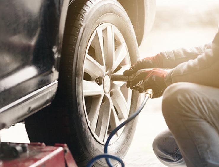 mies vaihtaa auton rengasta